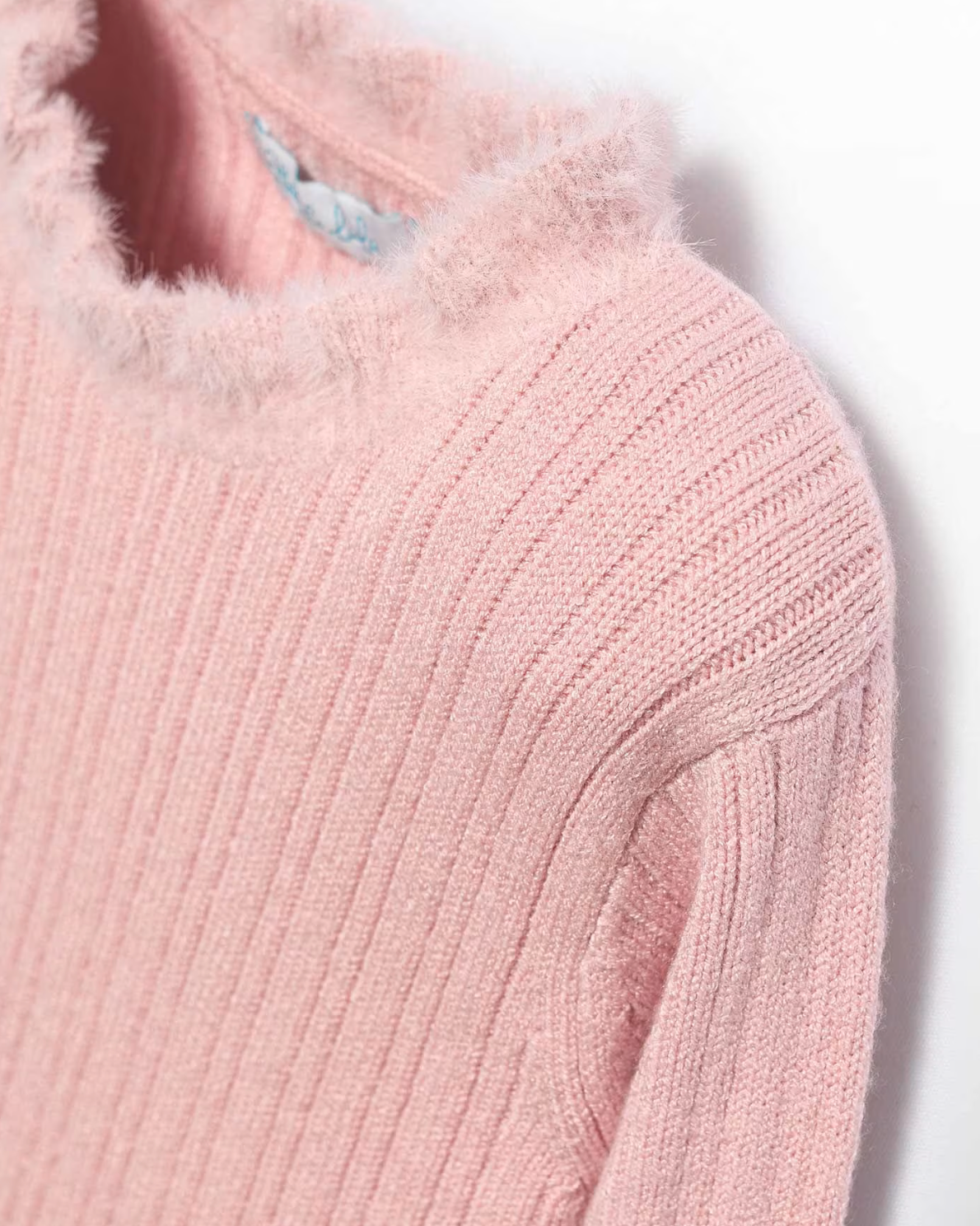 Close-up of a pink knitted sweater with fur trim on a white background