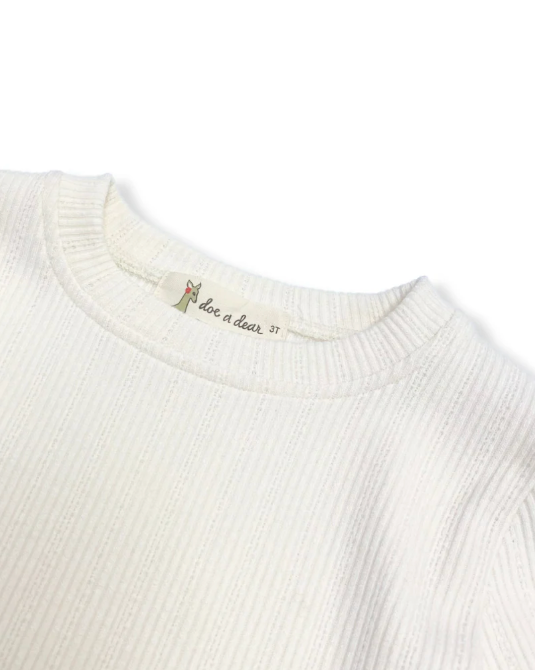 Close-up of a white ribbed sweater with a brand label on a white background