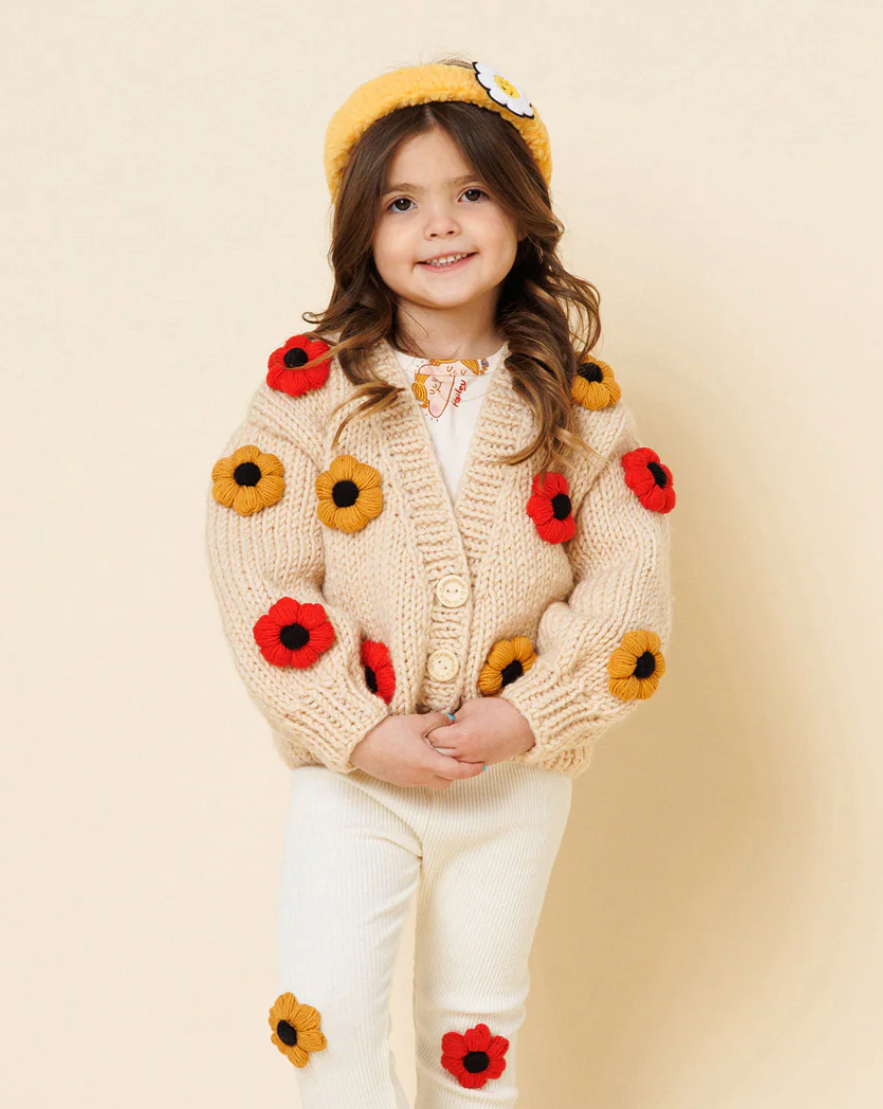 Child wearing a floral cardigan with a plain background
