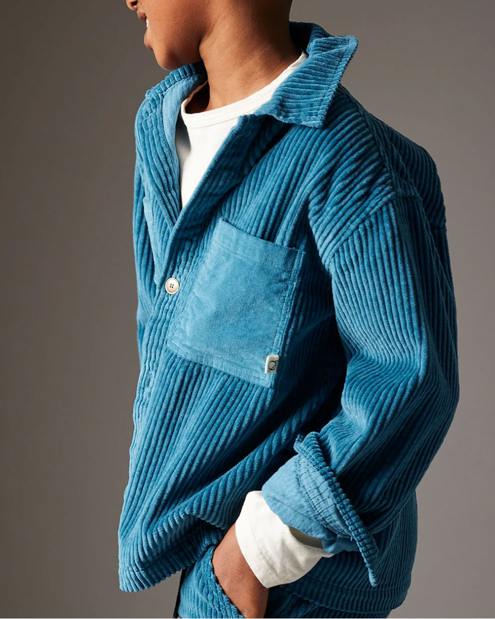 Person wearing a blue ribbed sweater against a gray background