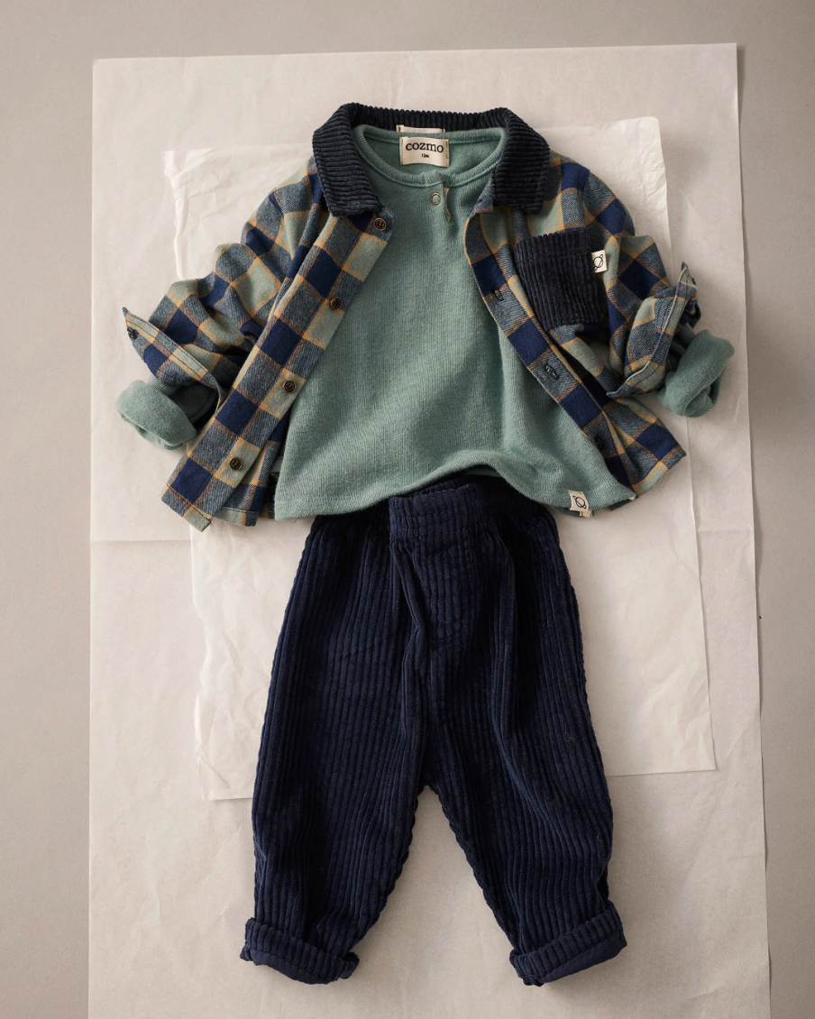 Children's outfit with green shirt, plaid jacket, and dark pants on a white background