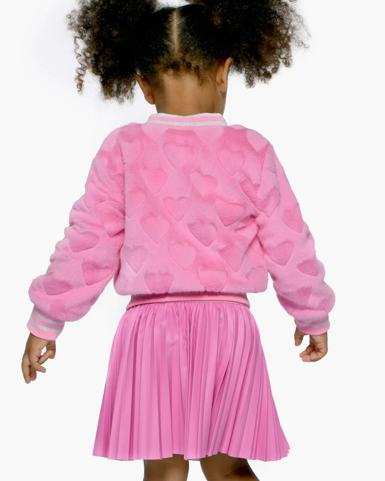 Child wearing a pink heart-patterned jacket and skirt on a white background
