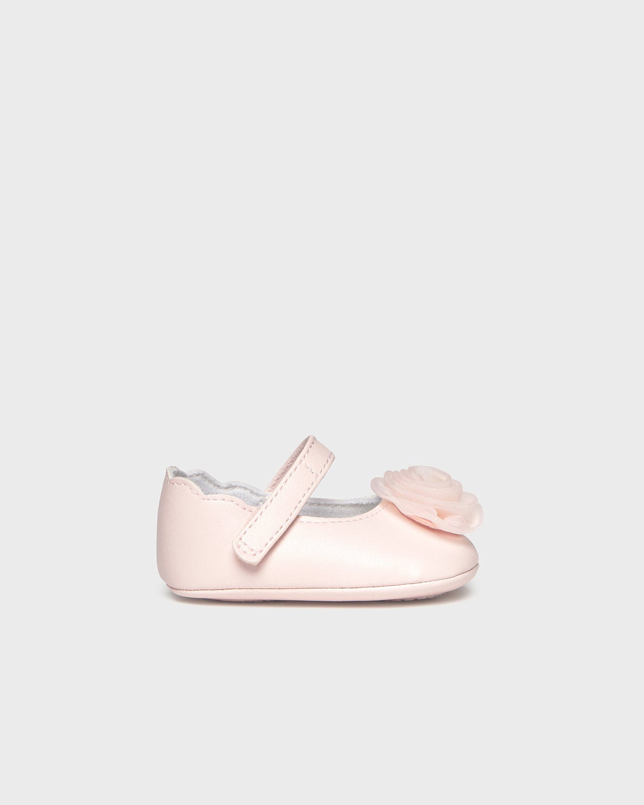 Pink baby shoe with a bow on a light gray background