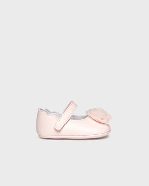 Pink baby shoe with a bow on a light gray background