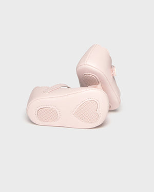 Pair of light pink baby shoes on a white background