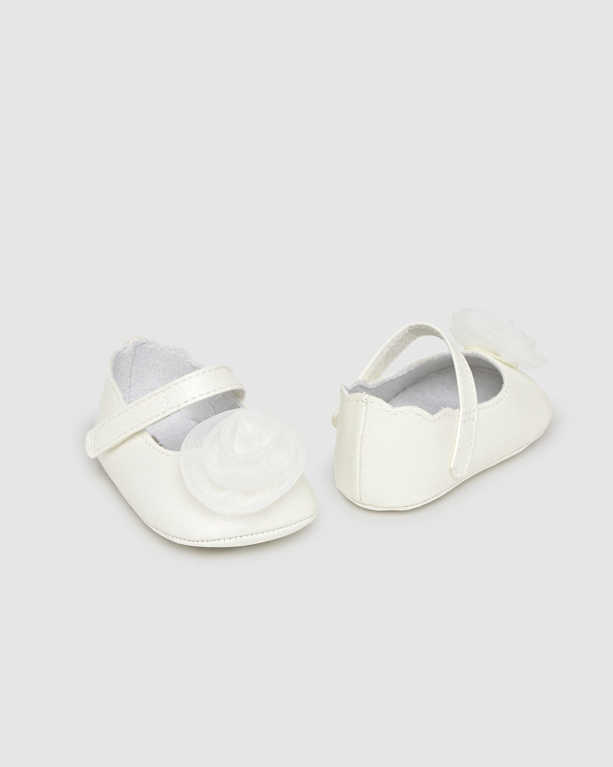 Pair of white baby shoes on a light gray background