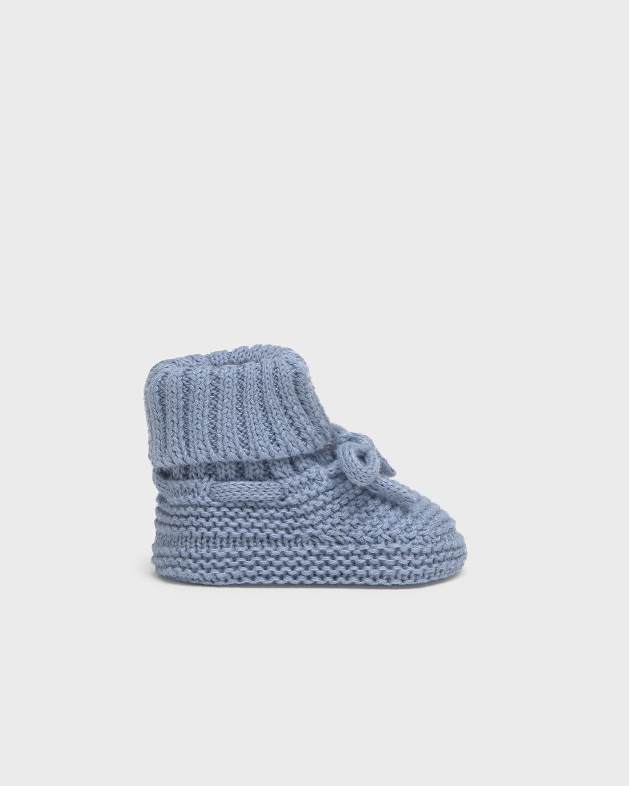 Knitted baby bootie on a light gray background