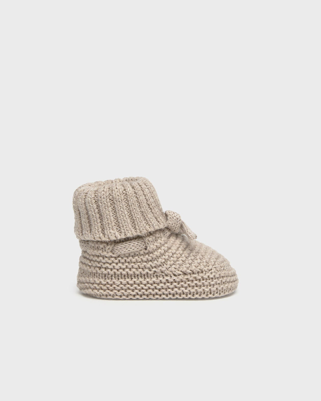 Knitted baby bootie on a light gray background